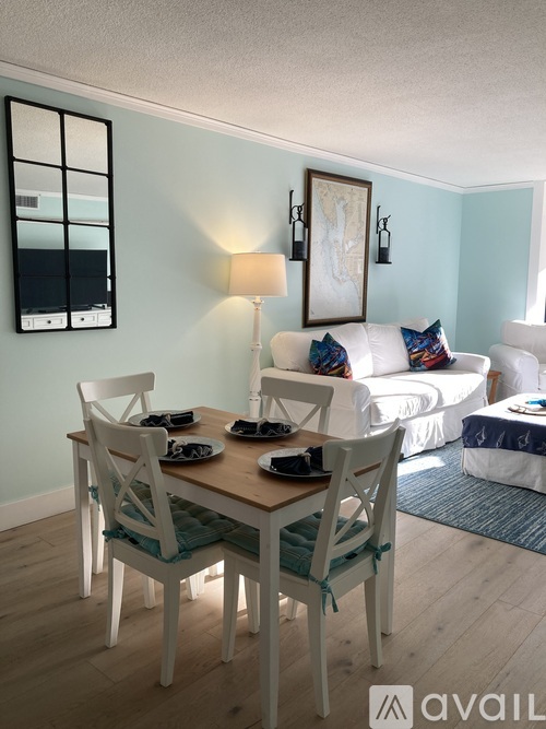 A dining room with a wooden table and white chairs.