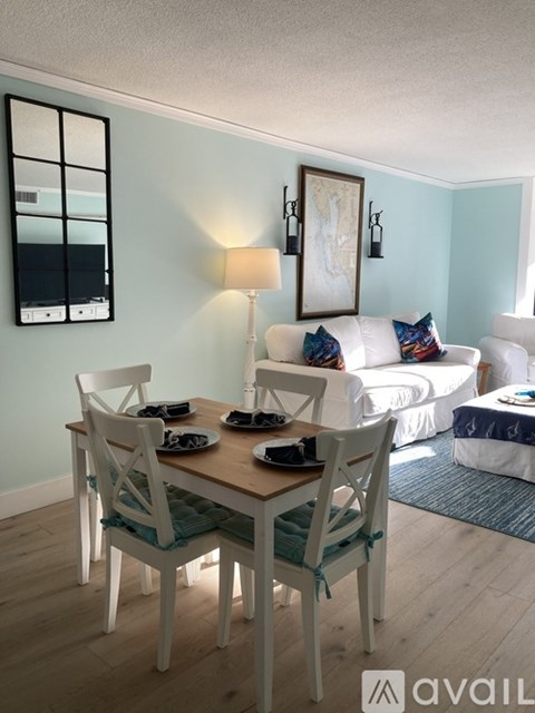 A dining room with a wooden table and white chairs.