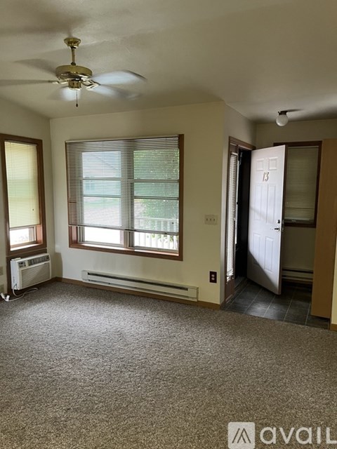 A room with a carpeted floor, a ceiling fan, and a window with blinds.