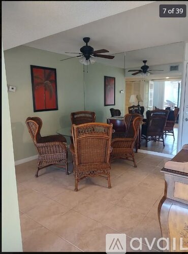 A living room with a ceiling fan and wicker chairs.