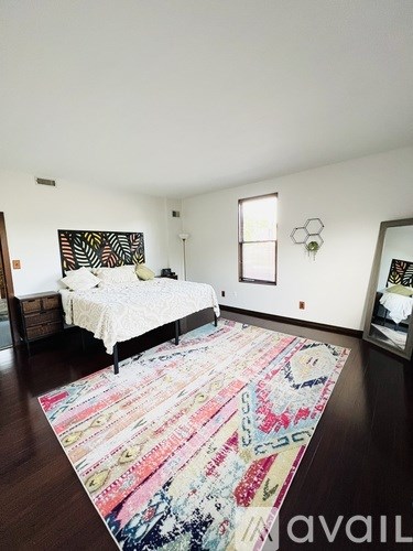 A bedroom with a large bed and a colorful rug.