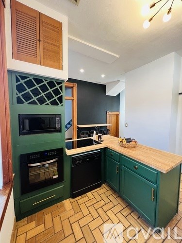 A kitchen with green cabinets and a wooden counter.