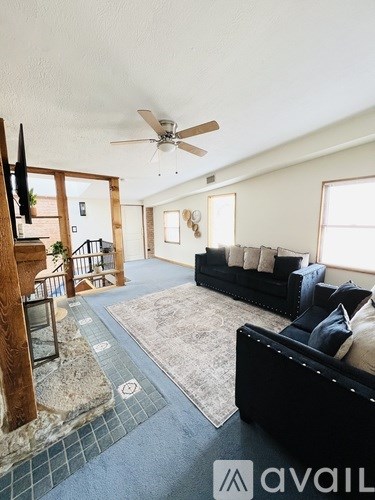 A living room with a black couch and a ceiling fan.