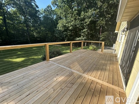 A wooden deck with a railing and a view of trees.