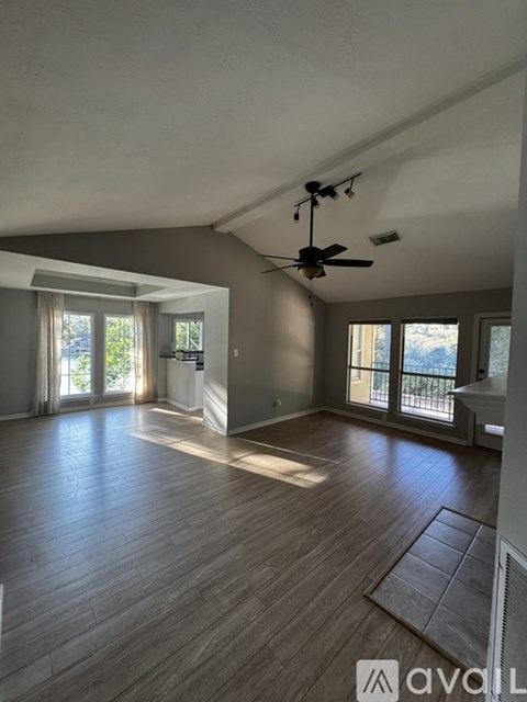 A spacious room with wooden flooring and a ceiling fan.