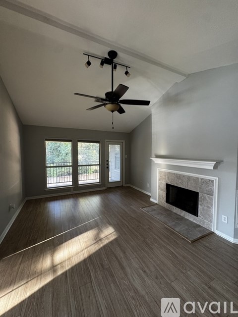 A living room with a fireplace and a ceiling fan.