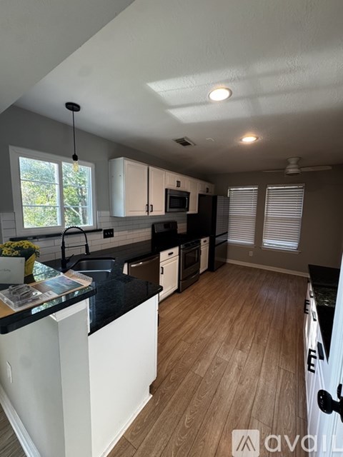 A kitchen with white cabinets and black countertops.