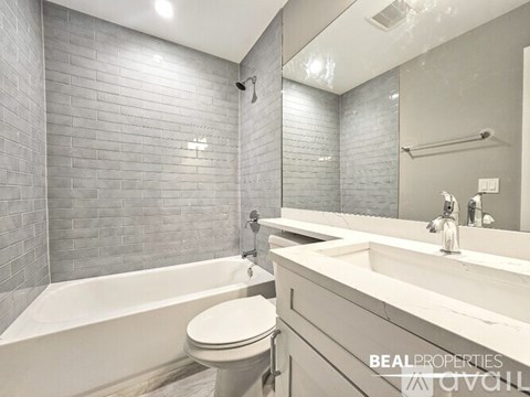 A modern bathroom with a white tub, sink, and toilet.