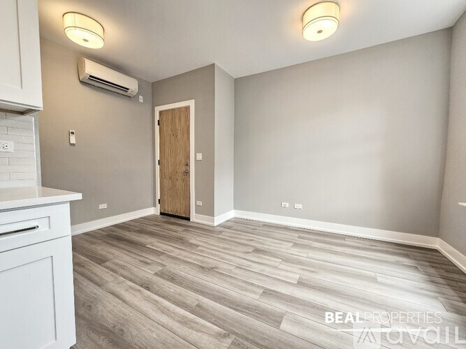 A spacious room with a wooden floor and a white cabinet on the left side.