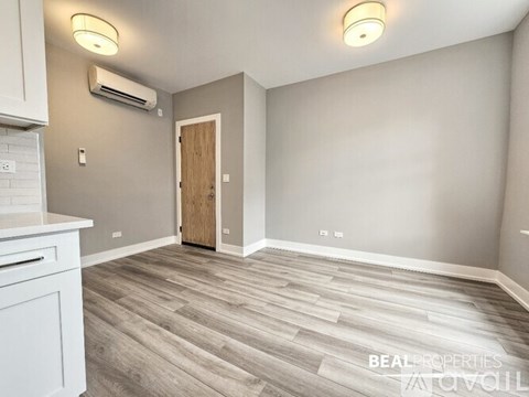 A spacious room with a wooden floor and a white cabinet on the left side.