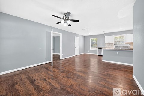 A spacious room with wood flooring and a ceiling fan.