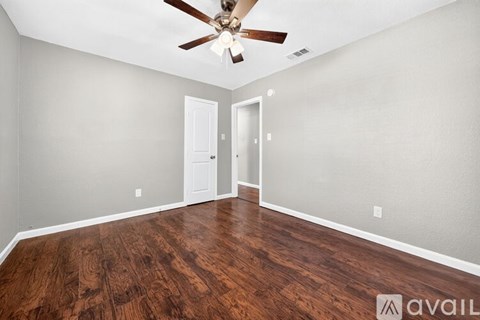 A room with a ceiling fan and wooden flooring.