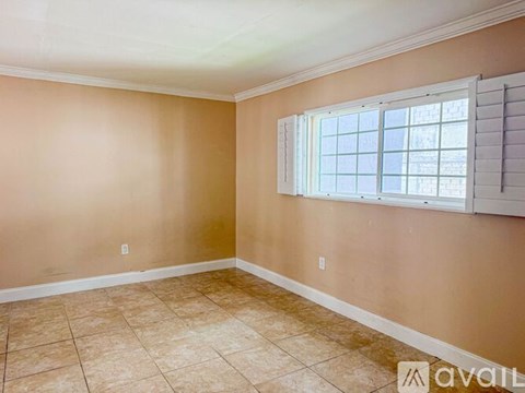 A room with beige walls and a window with blinds.