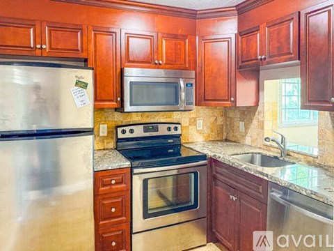 A kitchen with wooden cabinets and a stainless steel refrigerator.