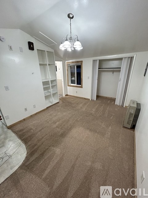 A room with a carpeted floor and a chandelier hanging from the ceiling.