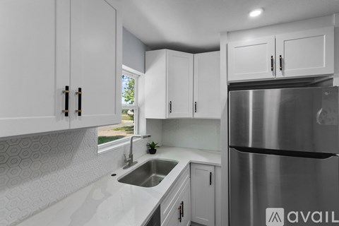 A modern kitchen with white cabinets and a stainless steel refrigerator.
