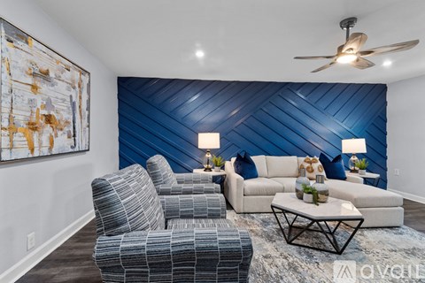 A living room with a blue wall and a painting on the wall.