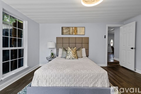 A bedroom with a large bed and a painting above it.