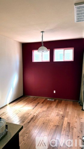 A room with a red wall and wooden flooring.