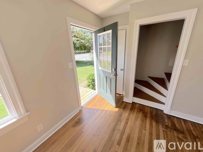 A room with a wooden floor and a door leading outside.