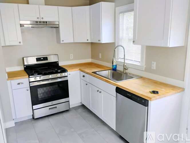 A kitchen with white cabinets and a wooden countertop.