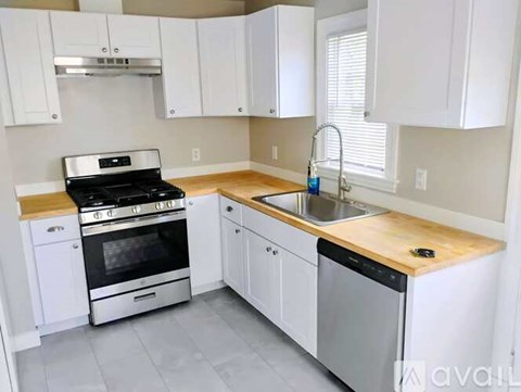 A kitchen with white cabinets and a wooden countertop.