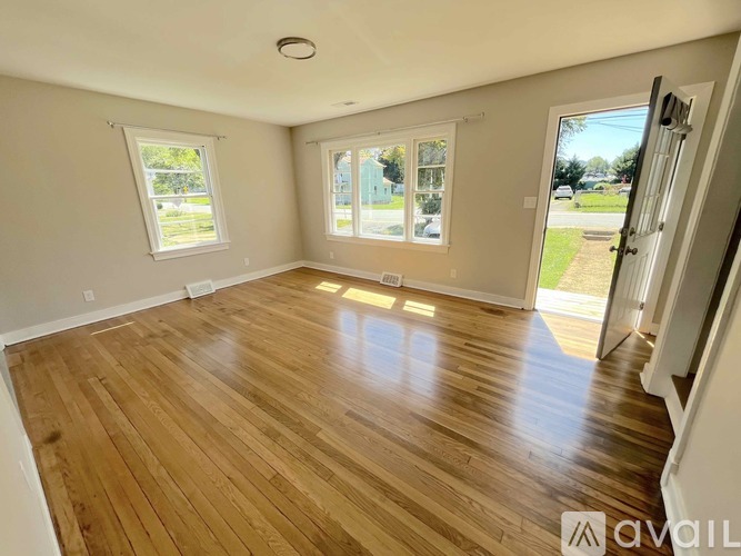 A room with wooden flooring and a sliding glass door leading to a grassy area.