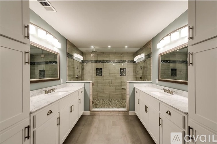 A bathroom with a walk-in shower and double sinks.