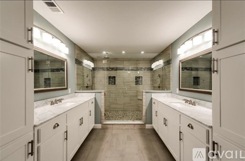 A bathroom with a walk-in shower and double sinks.