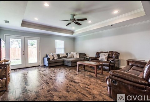 A living room with a brown leather couch and a ceiling fan.