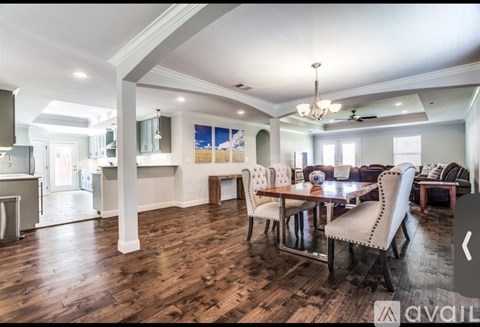 A spacious dining room with a wooden table and chairs.