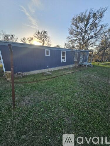 A blue building with a white door and a window is surrounded by a grassy area.