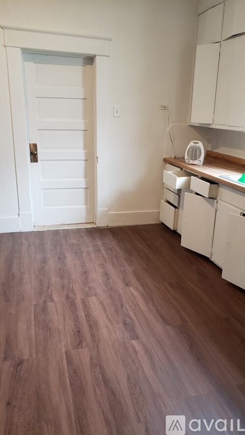 A kitchen with white cabinets and a wooden floor.