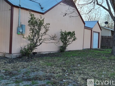 A house with a brown siding and a blue roof with a small tree in front.
