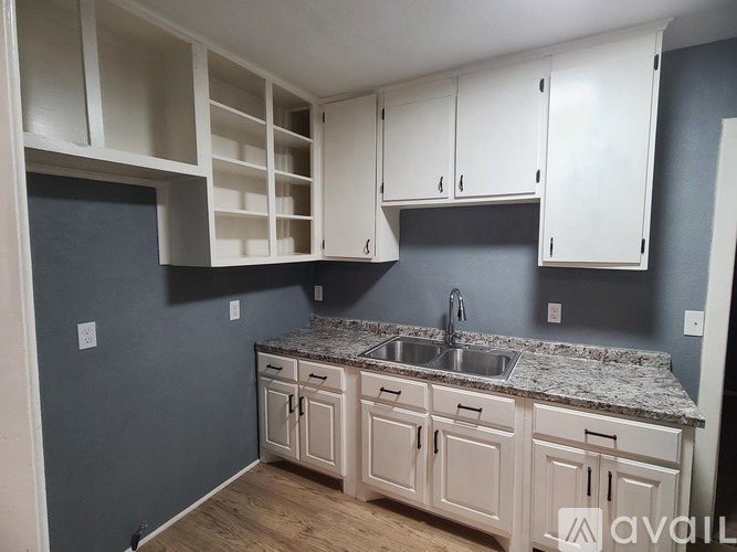 A kitchen with white cabinets and a granite countertop.