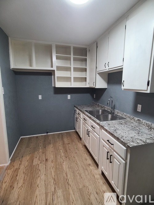A kitchen with white cabinets and a marble countertop.