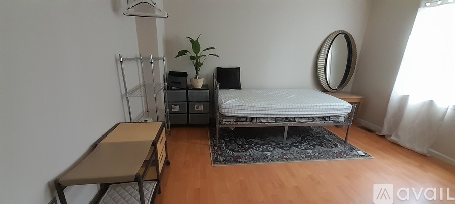 A bedroom with a bed, a mirror, a plant, and a desk.