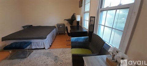 A bedroom with a bed, chair, and a window.