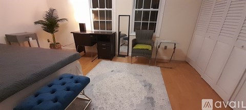 A bedroom with a bed, desk, chair, and a rug.