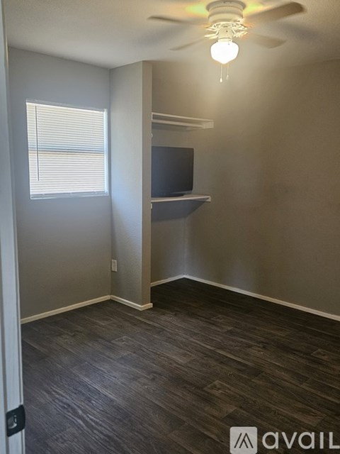 A room with a ceiling fan and a window with blinds.