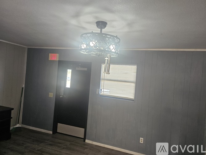 A room with a chandelier, a door, and a window.