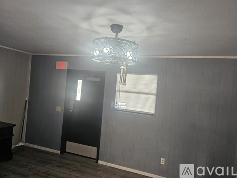 A room with a chandelier, a door, and a window.