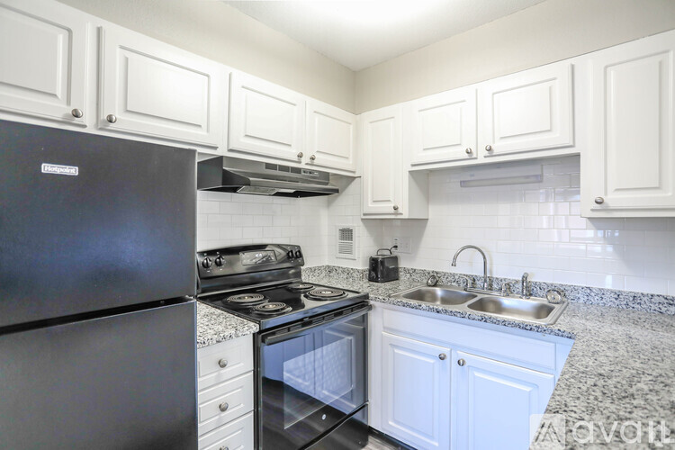 A kitchen with black appliances and white cabinets.
