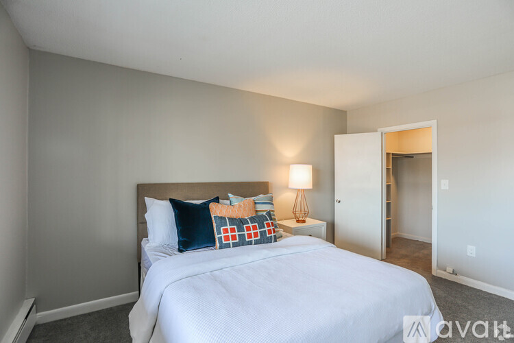 A bedroom with a bed, lamp, and a door leading to another room.