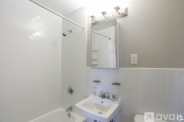 A white bathroom with a sink, mirror, and bathtub.
