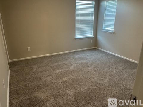 A carpeted room with two windows and a door.