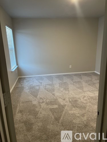 A carpeted room with a window on the left side.