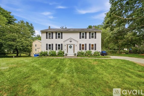 A large white house with a green lawn in front.