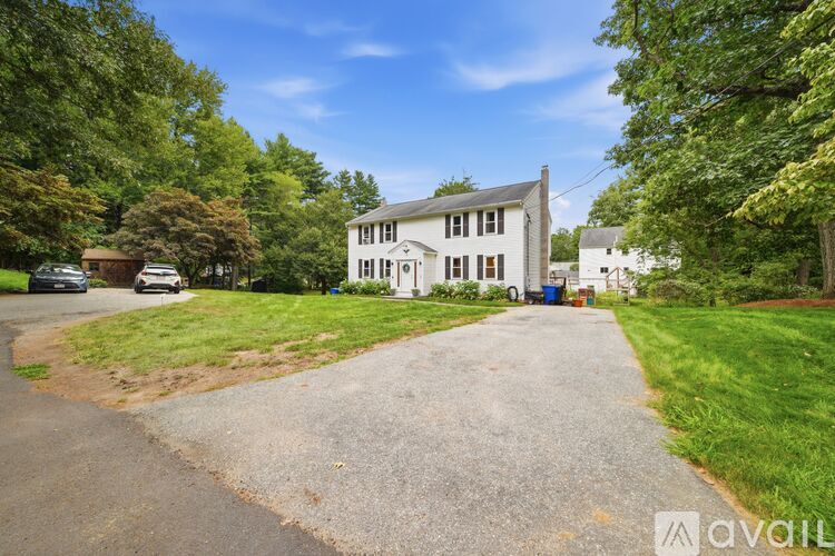 A house with a driveway in front of it surrounded by trees.