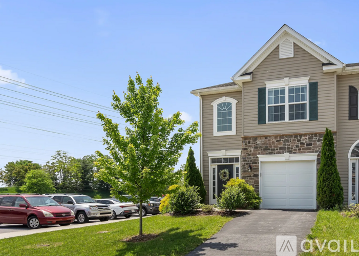 A house with a garage and a tree in front of it.